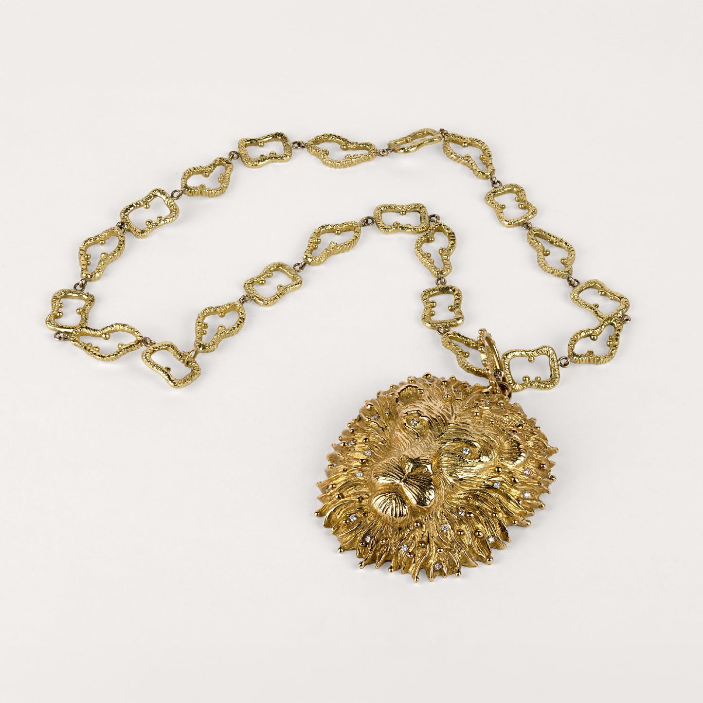 Pendentif Lion roi de la savane Cabinet de curiosité, bélière perlée, diamants et or jaune, accompagné de sa chaîne maille ciselée aux contours irréguliers en or jaune 18k 750/1000